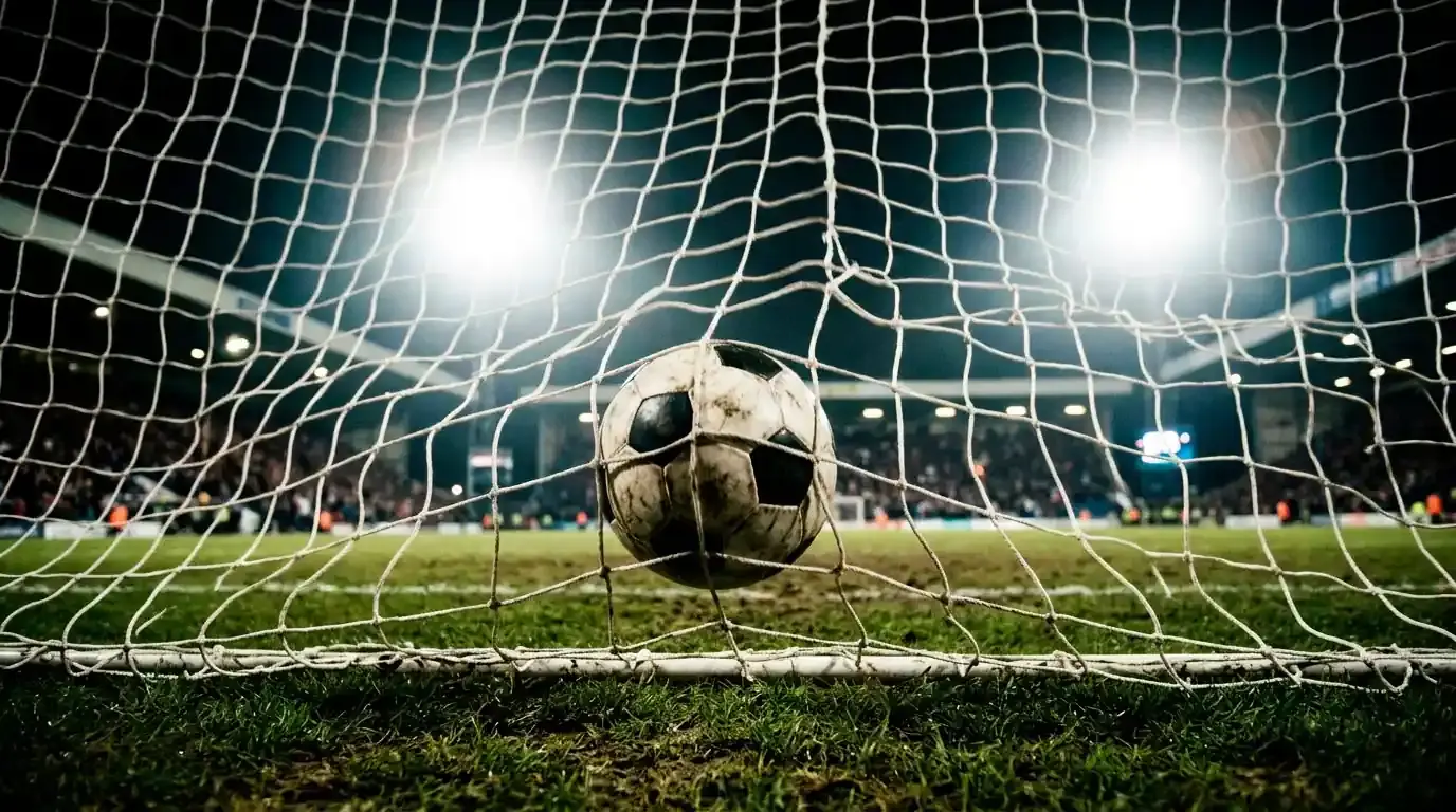 Dettaglio di un pallone in area con la rete della porta sullo sfondo, simbolo del gol storico in palio